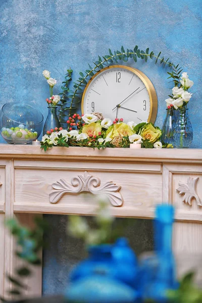 Taze çiçekler ve şöminenin üzerinde saat — Stok fotoğraf