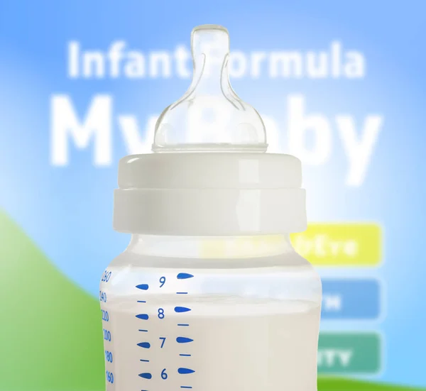 Feeding bottle with baby milk formula on blurred background