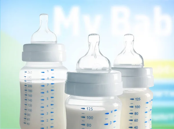 Feeding bottles with baby milk formula on blurred background