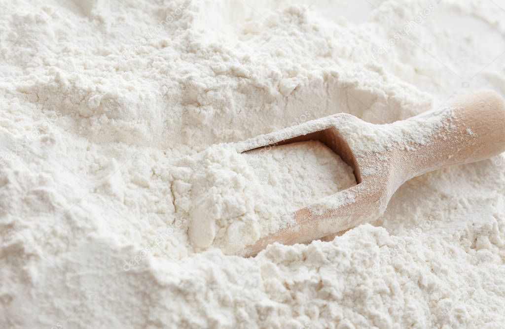 Wooden scoop on flour