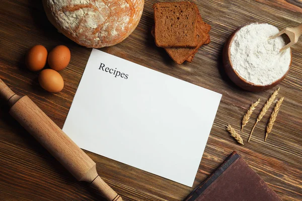 Hoja de papel en blanco e ingredientes para cocinar pan sobre fondo de madera —  Fotos de Stock