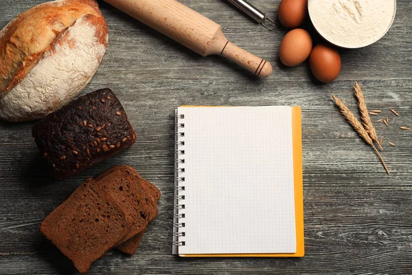 Notebook and ingredients for cooking bread on wooden background — Stock Photo, Image