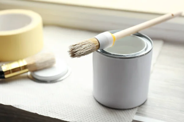 Can with paint and brush on window sill — Stock Photo, Image