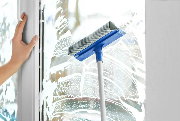 Hand of young man with mop washing window in office — Stock Photo, Image