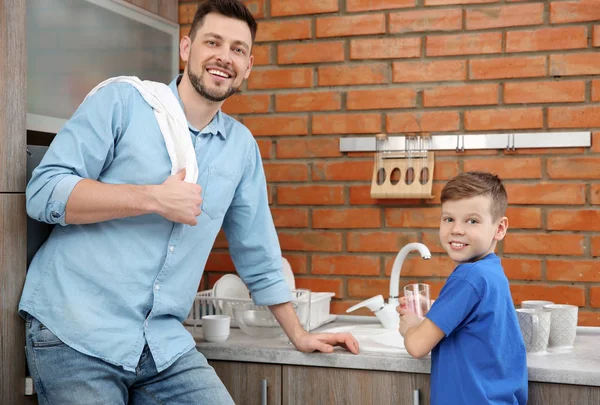 Папа и сын моют посуду на кухне. — стоковое фото