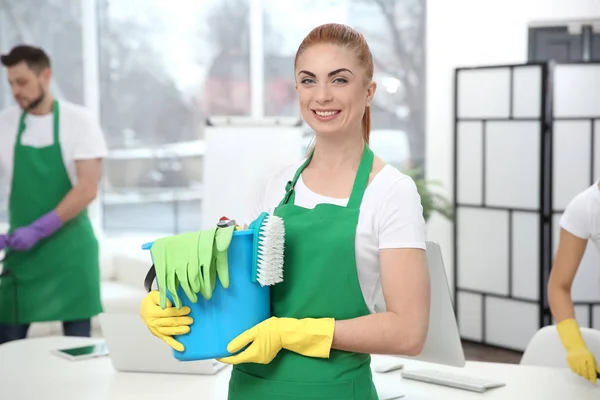 Trabajadora joven sosteniendo artículos de limpieza en la oficina — Foto de Stock