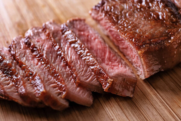 Sliced tasty steak on wooden board