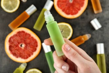 el ile parfüm şişe tutan ve narenciye dilimlenmiş 