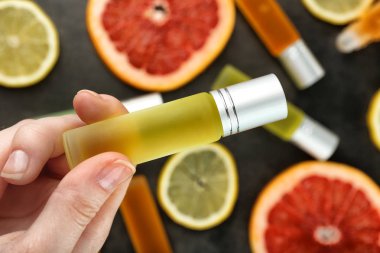 el ile parfüm şişe tutan ve narenciye dilimlenmiş 