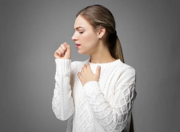 Mujer joven tosiendo sobre fondo gris —  Fotos de Stock