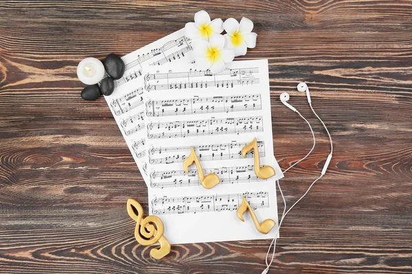 Composition of music sheets and spa supplies on wooden background