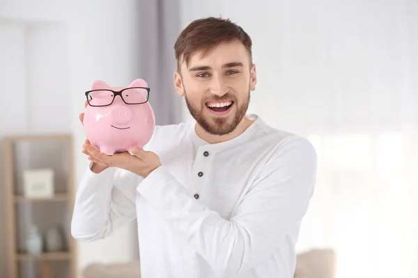 Feliz joven divirtiéndose con alcancía en casa — Foto de Stock