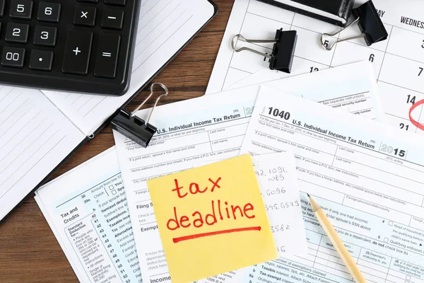 Hoja de papel con texto TAX DEADLINE y formulario de declaración de impuestos individual sobre la mesa — Foto de Stock