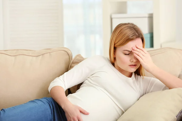 Zwangere vrouw liggend op de Bank thuis lijden aan hoofdpijn — Stockfoto