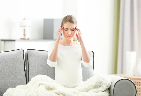 Беременная женщина, страдающая от головной боли, сидя дома на диване — стоковое фото
