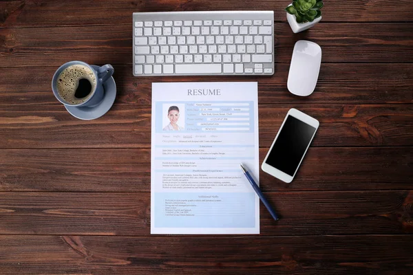 Resume, phone and keyboard on wooden table