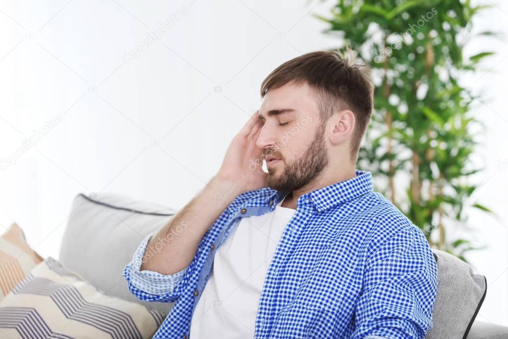 Young man suffering from headache at home