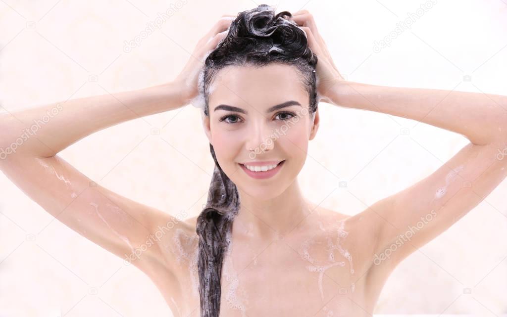 Beautiful young woman washing hair 