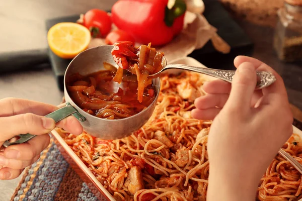 Женщина добавляет соус к куриным спагетти — стоковое фото