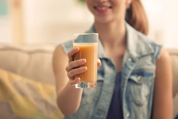 Young woman tasting fresh juice sitting on couch at living room — Stock Photo, Image