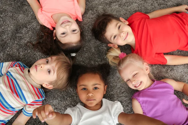 Милые маленькие дети, лежащие дома на ковре — стоковое фото