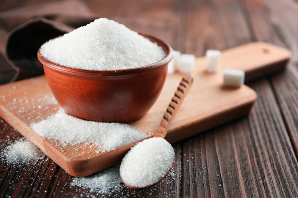 Schüssel und Löffel voller Zucker auf hölzernem Hintergrund — Stockfoto
