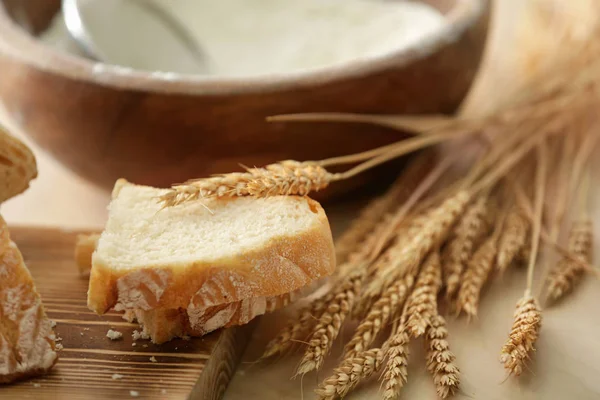 Bread, wooden board and wheat spikelets — Stock Photo, Image