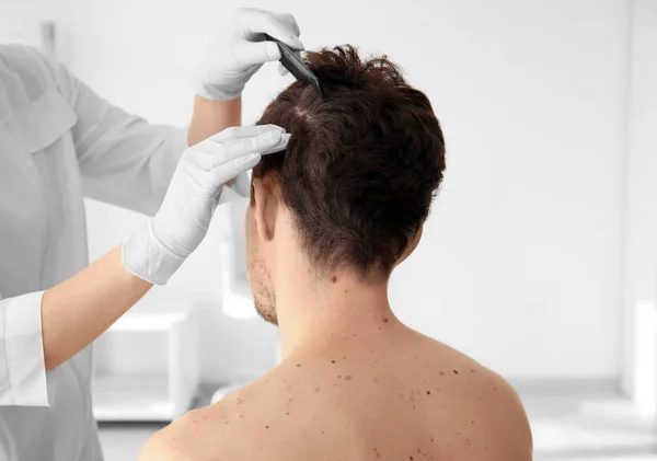 Dermatoloog onderzoekt patiënt in kliniek — Stockfoto