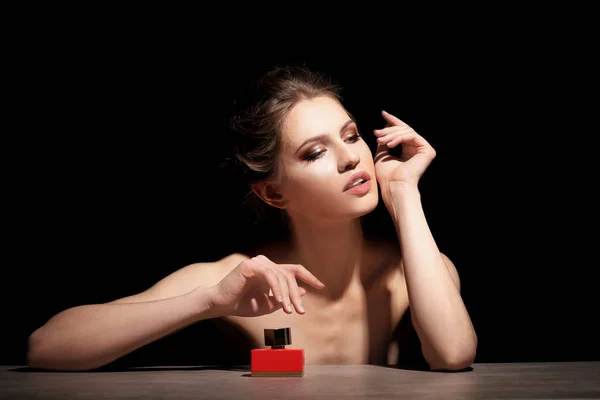 Beautiful young woman with bottle of perfume — Stock Photo, Image