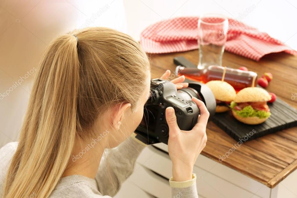 Young woman photographing food indoors