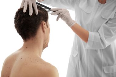 Dermatolog klinikteki hastayı muayene ediyor.