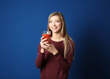 Güzel genç kadın ile bardak koyu mavi zemin üzerine taze meyve suyu