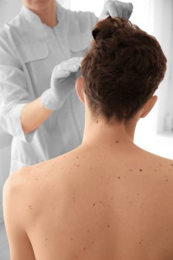 Dermatolog klinikteki hastayı muayene ediyor.