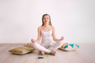 Meditasyon ve katta evde otururken müzik genç kadın