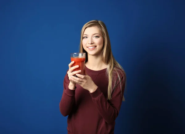 Mulher bonita com vidro de suco fresco no fundo azul escuro — Fotografia de Stock