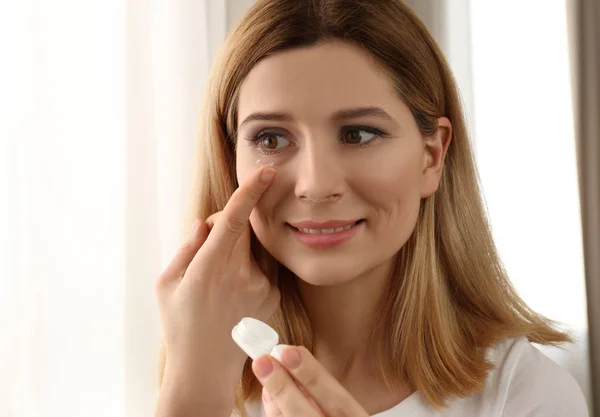 Mujer poniendo lentes de contacto sobre fondo claro — Foto de Stock