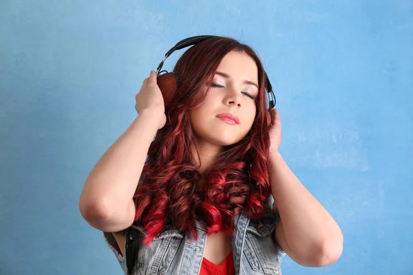 Красива молода жінка з фарбованим волоссям слухає музику на кольоровому фоні — стокове фото