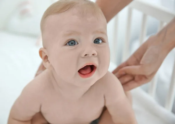 Madre manos sosteniendo pequeño bebé en cuna en el interior — Foto de Stock