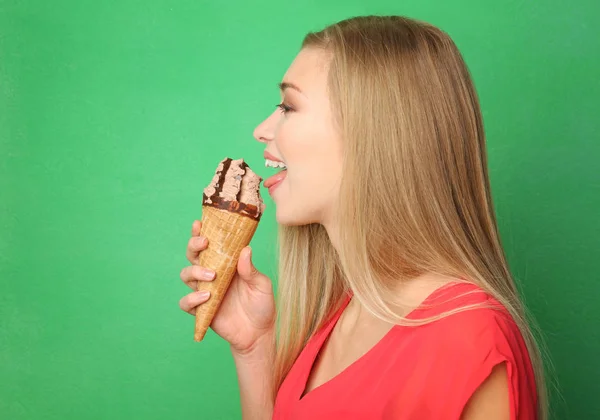 Beautiful young woman eating ice cream on color background — Stock Photo, Image