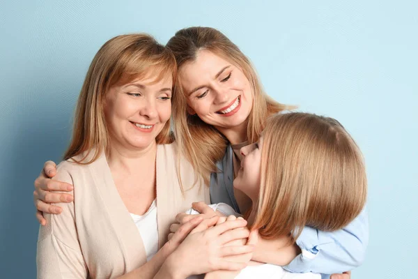 Glad ung kvinna med hennes mor och dotter på färgbakgrund — Stockfoto