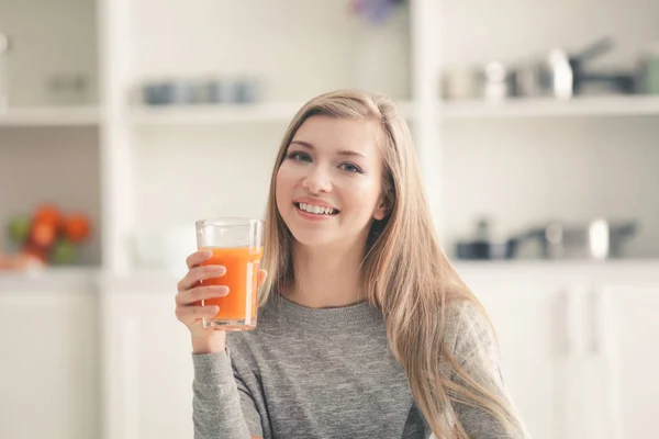 Mujer joven con vaso de jugo fresco en la cocina —  Fotos de Stock