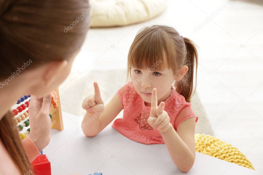 Cute little girl learning to count at private teacher's office