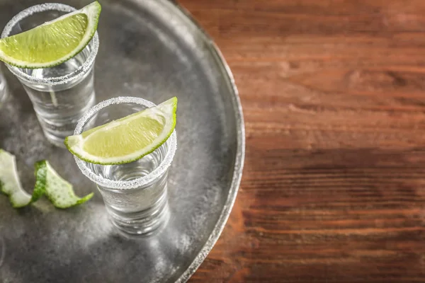 Tequila shots with juicy lime slices and salt on tray — Stock Photo, Image