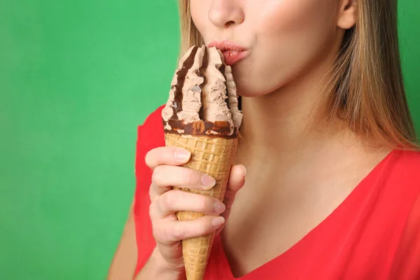 Hermosa joven comiendo helado sobre fondo de color — Foto de Stock