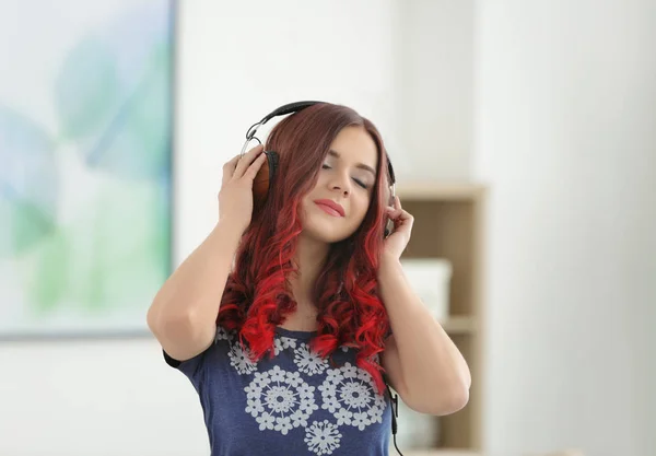 Hermosa joven con el pelo teñido escuchando música en casa — Foto de Stock