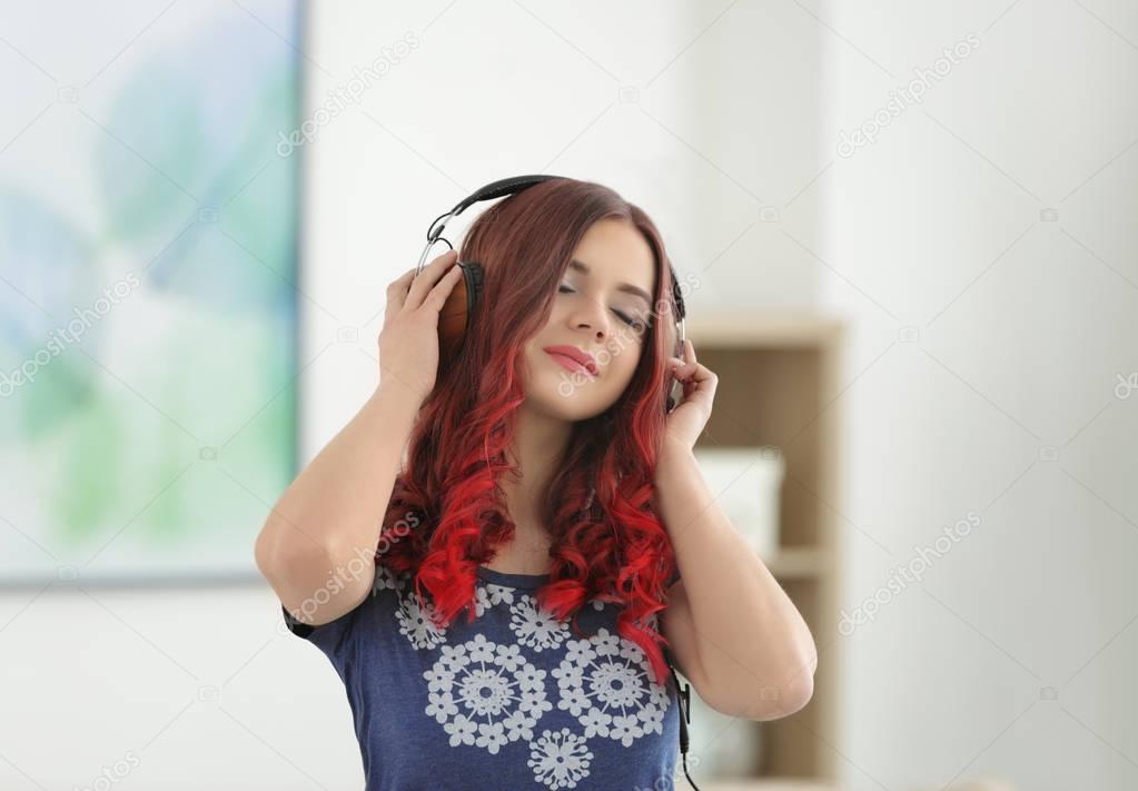Beautiful young woman with dyed hair listening to music at home