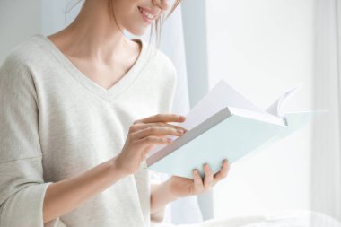Güzel genç kadın pencere evde, closeup yakınındaki kitap okuma