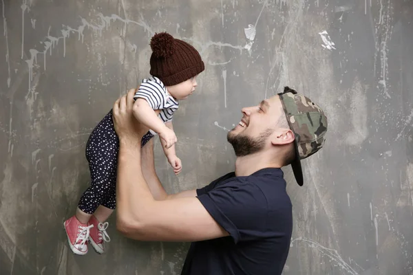 Far poserar med söt baby dotter på grunge bakgrund — Stockfoto