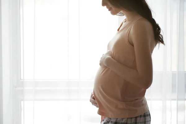 Mooie zwangere vrouw permanent in de buurt van venster thuis — Stockfoto