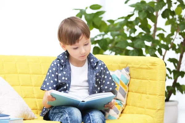 Милый маленький мальчик читает дома книги — стоковое фото
